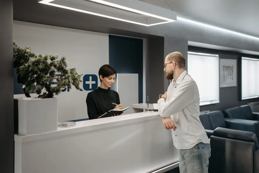 A patient checking in at a bright clinic reception desk