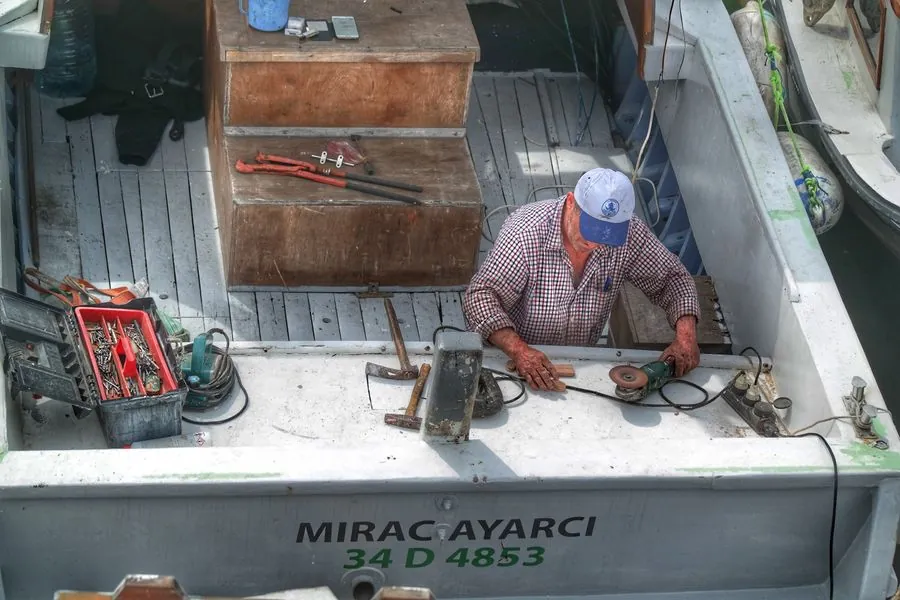 A mechanic working on equipment on a boat deck at the dock