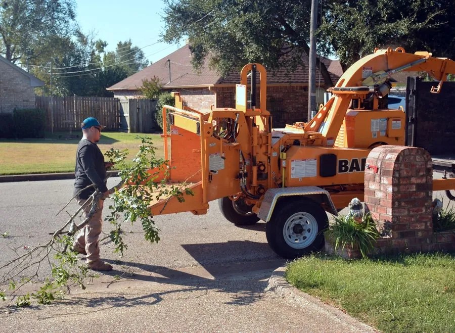 A crew member feeding branches into a wood chipper
